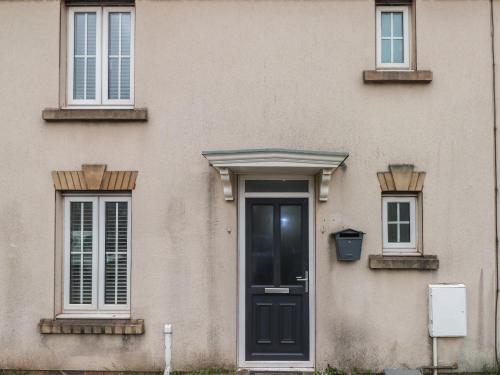 a house with a black door and two windows at 39 Mariners Quay in Port Talbot