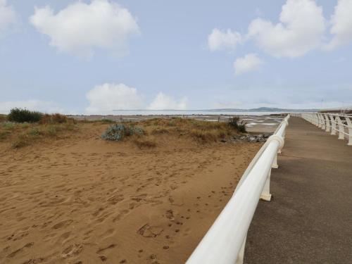 a sandy beach with a white boardwalk next to the ocean at 39 Mariners Quay in Port Talbot
