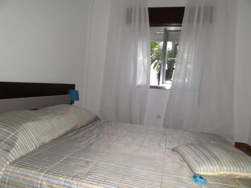 a bed in a bedroom with a window at Residencial Espadinha in Quarteira