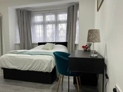 a bedroom with a bed and a desk and a window at Starlet Property in Wanstead