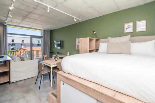 a bedroom with a large bed and a dining room at Brand New Seapoint Apartment in Cape Town