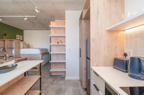 een keuken met witte werkbladen en een bed in een kamer bij Brand New Seapoint Apartment in Kaapstad