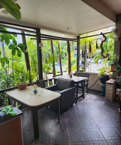 a restaurant with tables and chairs and plants at Bungalows Musch Kamala Phuket in Kamala Beach