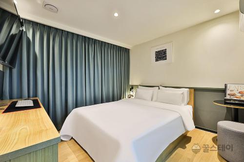 sypialnia z dużym białym łóżkiem i biurkiem w obiekcie No25 Hotel Bupyeong w mieście Inczon