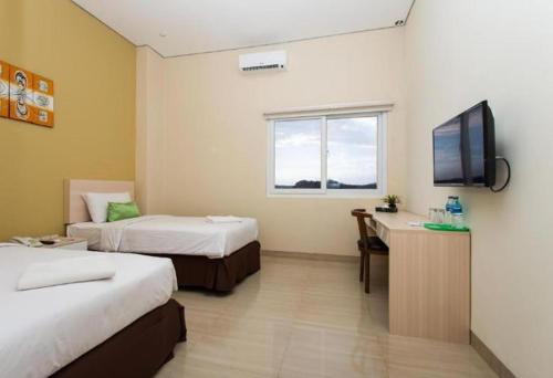 Habitación de hotel con 2 camas y TV de pantalla plana. en Best Inn Balikpapan en Balikpapan