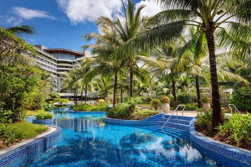 una piscina con palmeras frente a un hotel en Best Western Premier Sonasea Phu Quoc en Phu Quoc