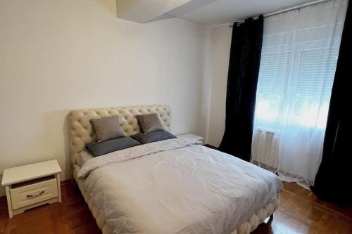 une chambre avec un grand lit blanc avec une fenêtre dans l'établissement Biser apartman, à Belgrade