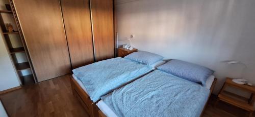 a small bedroom with a bed with blue sheets at Apartmán Nelka pri Muránskej Planine 