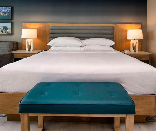 a bedroom with a large bed with a blue ottoman at Inn at the Pier Pismo Beach, Curio Collection by Hilton in Pismo Beach