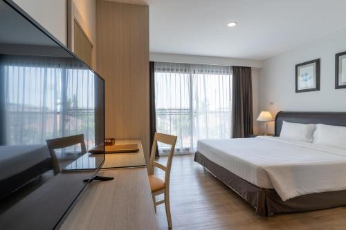 a hotel room with a bed and a desk and windows at Kantary Bay Hotel And Serviced Apartments Sriracha in Si Racha