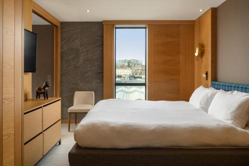 Un dormitorio con una gran cama blanca y una ventana en Market Street hotel en Edimburgo