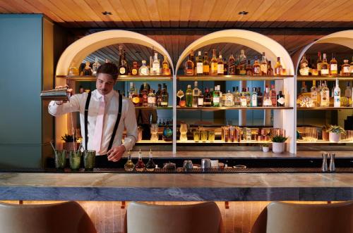 a man standing behind a bar with a drink at Taj 51 Buckingham Gate Suites and Residences in London