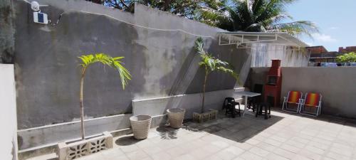 a patio with two palm trees and a wall at Casa do Léo 2 - Temática Egito e Japão in João Pessoa
