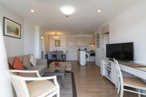 a living room with a couch and a tv and a kitchen at Kantary Bay Hotel And Serviced Apartments Sriracha in Si Racha