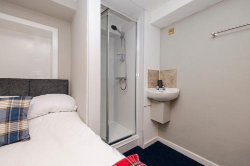 a bathroom with a shower and a bed and a sink at New Town Rooms in Edinburgh