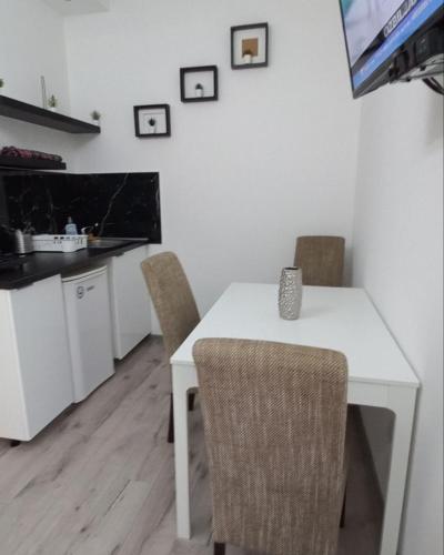 einen weißen Esstisch mit Stühlen und einen TV in der Unterkunft Apartmani Banja Vrujci Lux in Gornja Toplica