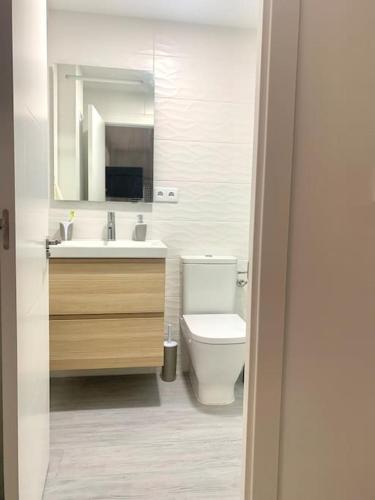 a bathroom with a toilet and a sink and a mirror at NEW STYLISH BEACH FRONT APARTMENT in Cullera