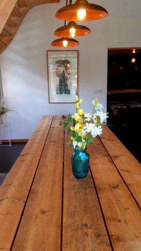 a wooden table with a vase of flowers on it at Maison-indi in Houffalize