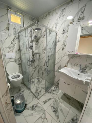 a bathroom with a shower and a toilet and a sink at Mila Pansiyon in Cıralı