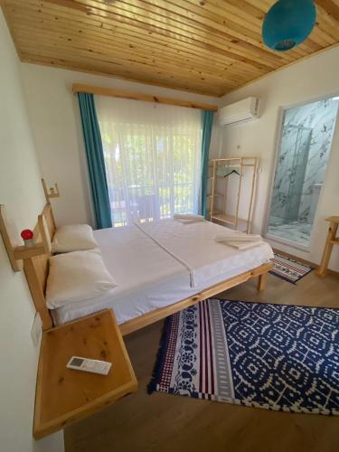a bedroom with a bed and a window and a rug at Mila Pansiyon in Cıralı