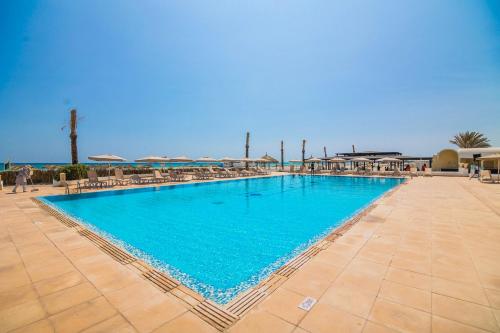 a large swimming pool with chairs and umbrellas at TMK Marine Beach - All Inclusive Seafront resort in Triffa