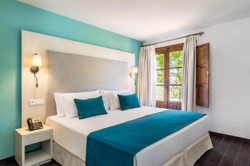 una camera da letto con un grande letto con accenti blu di Occidental Pueblo Acantilado a El Campello