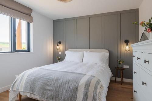 a bedroom with a white bed with a large window at Apartment 8, Forest Cove in Hope-Cove
