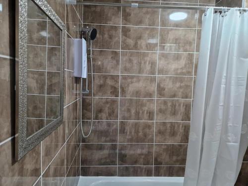 Impeccable 1-Bed Apartment in Ilford في إلفورد: حمام مع دش مع مرآة وحوض استحمام
