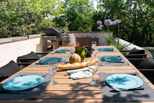 Maison d’Etienne في لاكوست: طاولة خشبية مع لوحات زرقاء واكواب للنبيذ