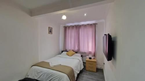 Captivating 2-Bed Apartment in Ilford في إلفورد: غرفة نوم بسريرين ونافذة ذات ستائر وردية