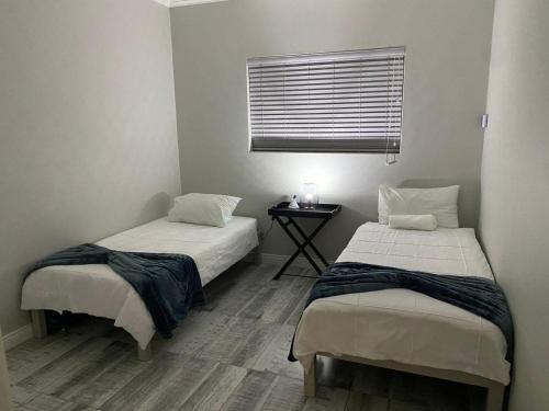 two beds in a small room with a window at Bliss at Diaz in Mossel Bay