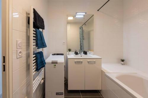 ein weißes Badezimmer mit einem Waschbecken, einer Badewanne und einem Waschbecken in der Unterkunft Les Jardins d'Aix in Aix-les-Bains