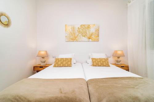 duas camas num quarto branco com duas lâmpadas em Juan Bravo Suites em Madri