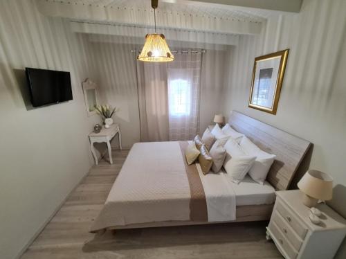 a white bedroom with a bed and a television at Ornament: Infinite Nature Villa in Dhafnés