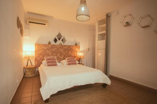 une chambre avec un grand lit blanc avec deux oreillers dans l'établissement Le Vacoa, à La Saline les Bains