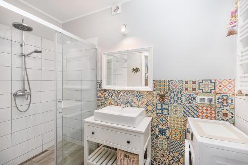 biała łazienka z umywalką i prysznicem w obiekcie Apartament Prowansalski w Rewalu