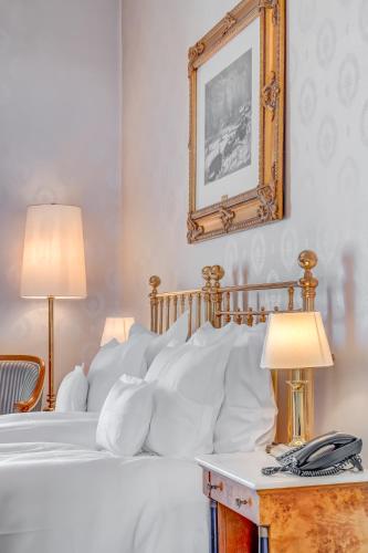 a bedroom with a bed with white pillows and a mirror at Grand Hotel National Luzern in Luzern