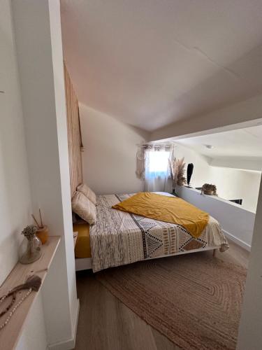 - une petite chambre avec un lit et une couverture jaune dans l'établissement Bienvenue chez moi, à Vic-la-Gardiole