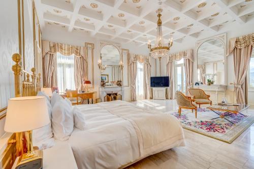 a bedroom with a large white bed and a chandelier at Grand Hotel National Luzern in Luzern