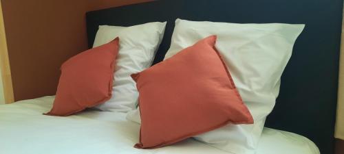 - 2 oreillers rouges assis au-dessus du lit dans l'établissement New Le 7 Clim Central Calme Parking Volumes, à Carcassonne