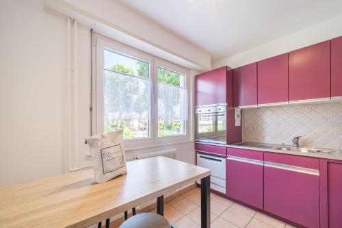 une cuisine avec des placards violets et une table en bois dans l'établissement La Symphonie - Joli appt à Colmar, à Colmar