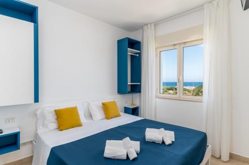 sypialnia z niebiesko-białym łóżkiem i oknem w obiekcie Calanca Apulian Residence w mieście Torre Santa Sabina