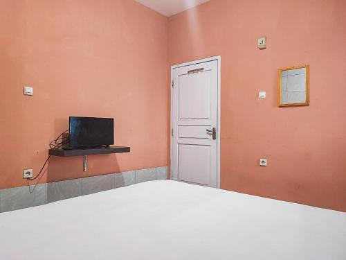 a bedroom with a bed and a door and a television at Reddoorz Syariah Near Kantor Gubernur Jambi in Jambi
