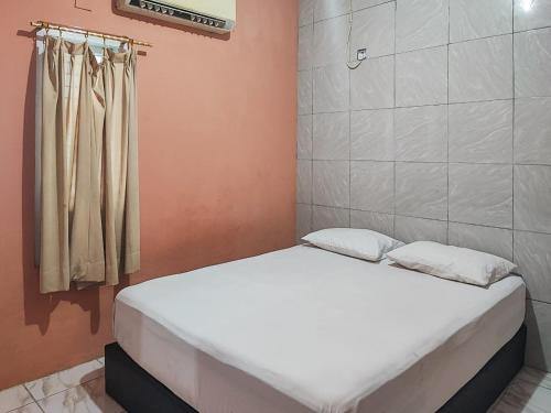 a small bedroom with a white bed in a room at Reddoorz Syariah Near Kantor Gubernur Jambi in Jambi
