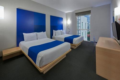 a hotel room with two beds and a television at City Express Plus by Marriott Ciudad de México Reforma El Ángel in Mexico City
