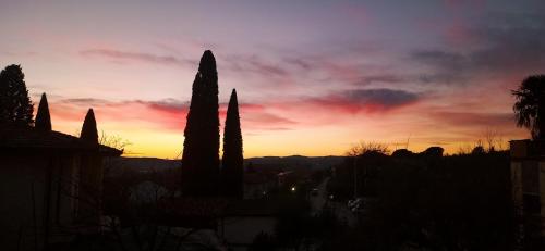 a sunset over a city with cypress trees at La Superba Ca' Zeneize in Foiano della Chiana