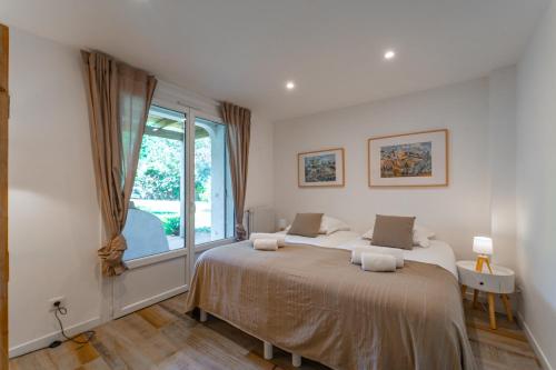 une chambre avec un grand lit et une fenêtre dans l'établissement Lulli - Spacieux appartement en rez de jardin, à Arcachon