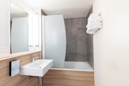 La salle de bains est pourvue d'un lavabo, d'une baignoire et d'un miroir. dans l'établissement Campanile Reims Ouest - Tinqueux, à Reims