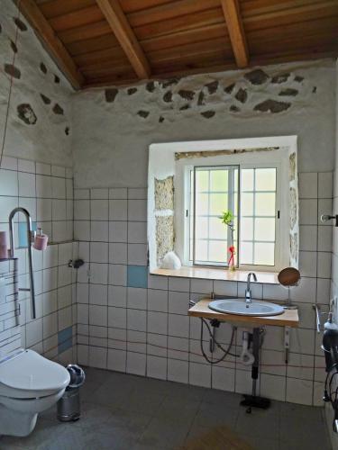 baño con lavabo, ventana y aseo en Casa dos Sonhos, en Fajazinha