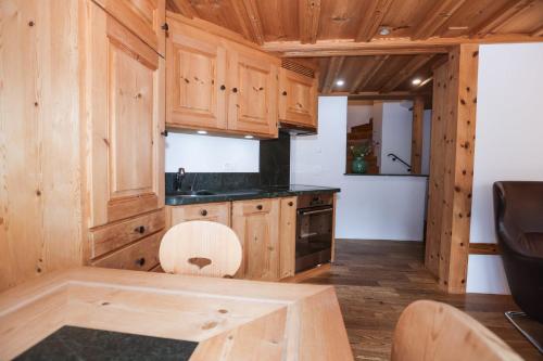 a kitchen with wooden cabinets and a wooden table at Casa LA RODA in Sedrun